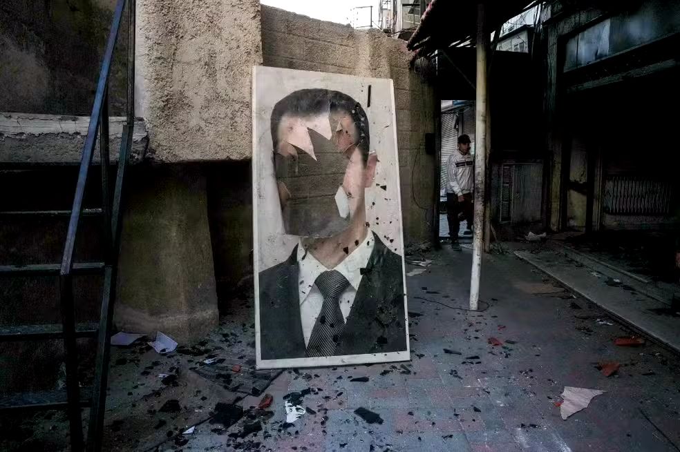 Síria: retrato rasgado do presidente sírio deposto Bashar al-Assad em uma instalação de segurança governamental saqueada, em Damasco, em 8 de dezembro de 2024.